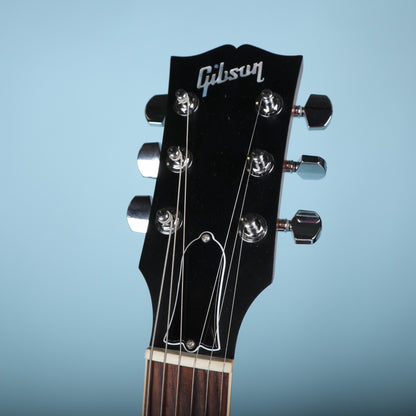 Front of headstock showing cursive Gibson logo and black truss rod cover