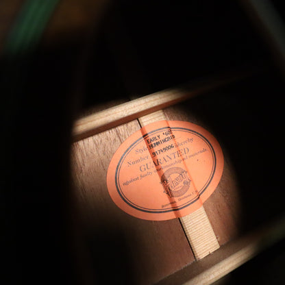 Interior view of the soundhole showing the orange oval label printed with 'EARLY '60S Style HUMMINGBIRD' and serial number 91749006.