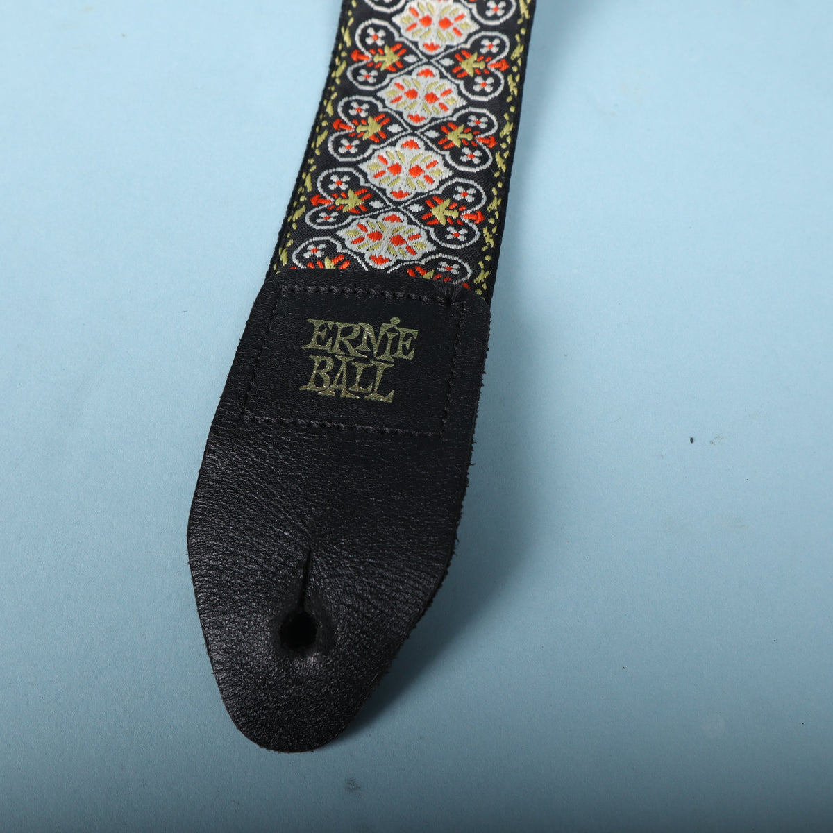 Close-up of the black leather end tab stamped with the gold Ernie Ball logo