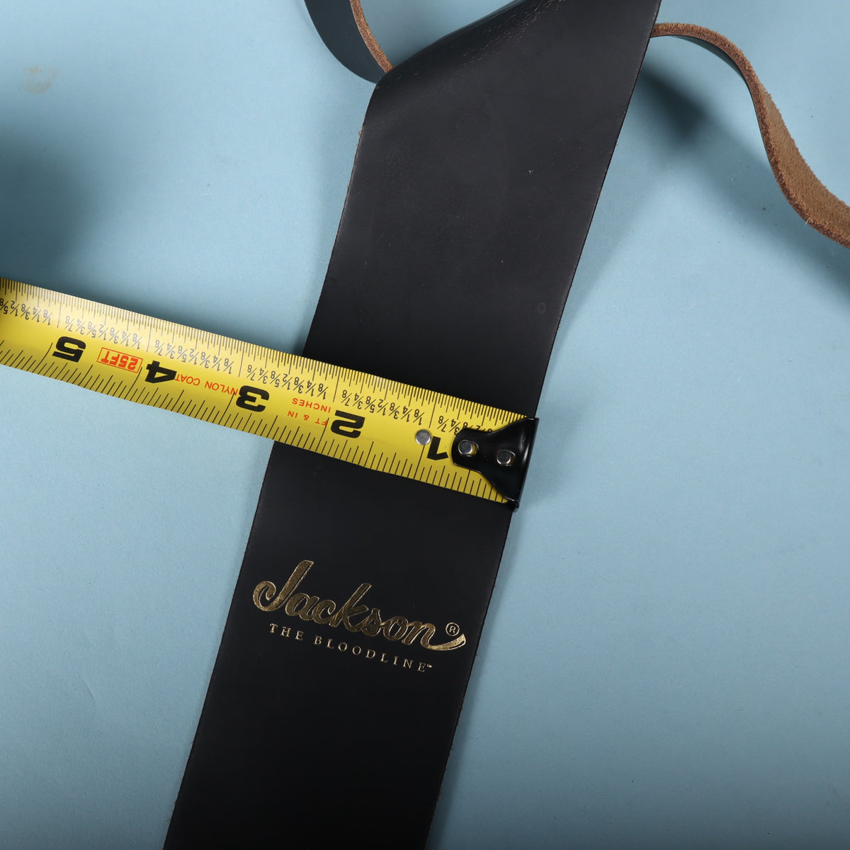 Jackson The Bloodline leather guitar strap measured with a tape measure showing 2.5 inch width