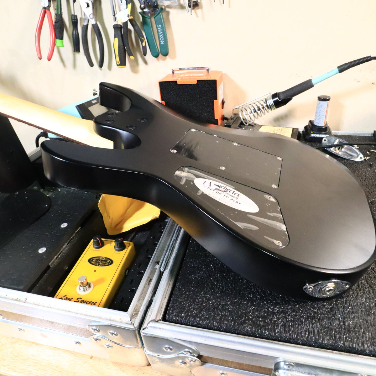 Rear view of the guitar body resting on a workbench showing cavity covers.
