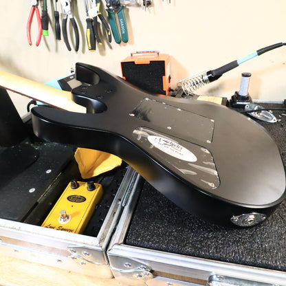 Rear view of the guitar body resting on a workbench showing cavity covers.