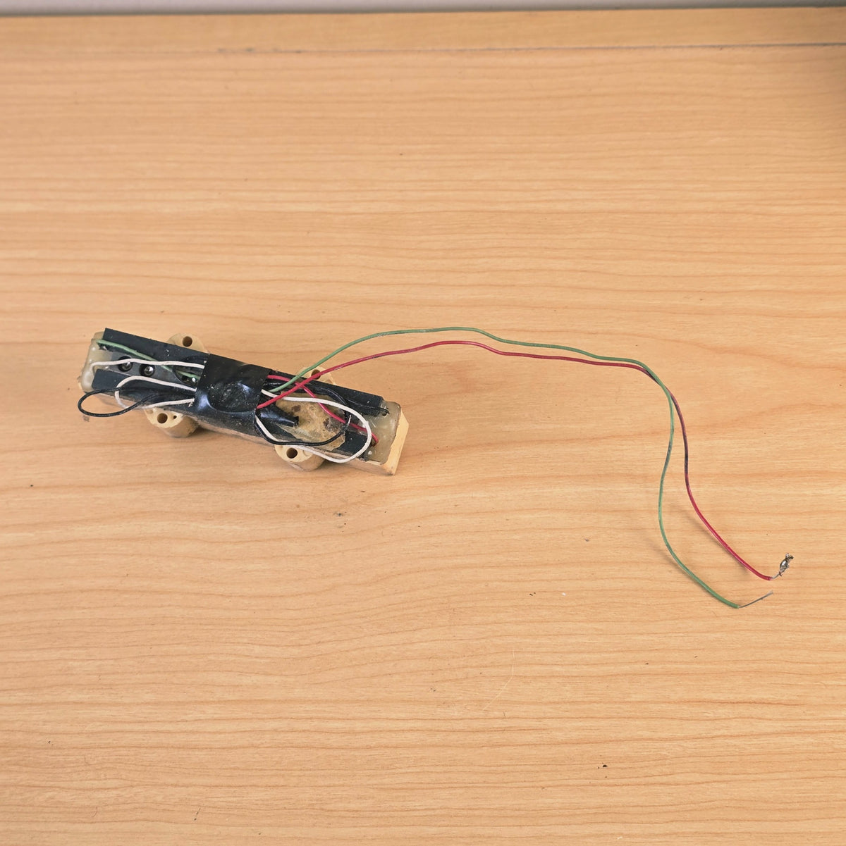 Bottom view of bass pickup showing electrical tape and wiring connections.