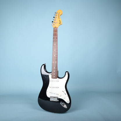 Full front view of Squier Stratocaster electric guitar in black on blue background.