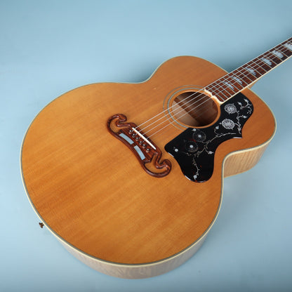 Angled front view of guitar body highlighting natural finish top and floral pickguard.