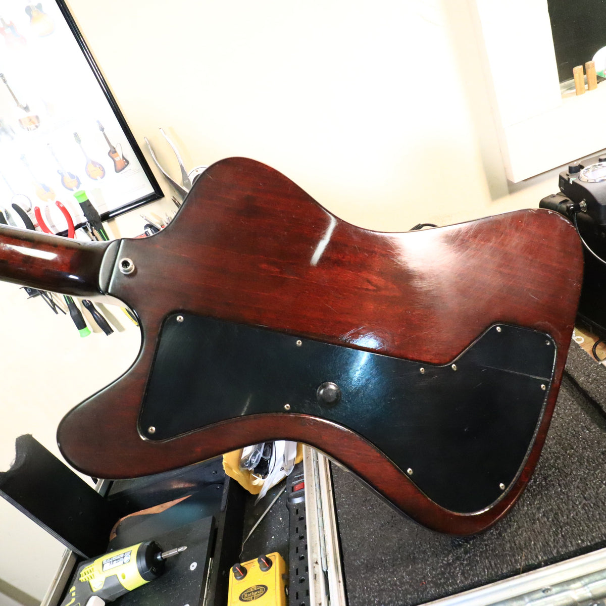 Back of the guitar body resting on a workbench showing finish condition and the large control cavity plate.