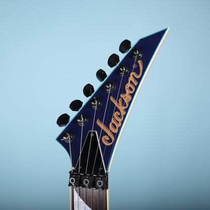 Front view of pointed Jackson headstock with gold logo and locking nut