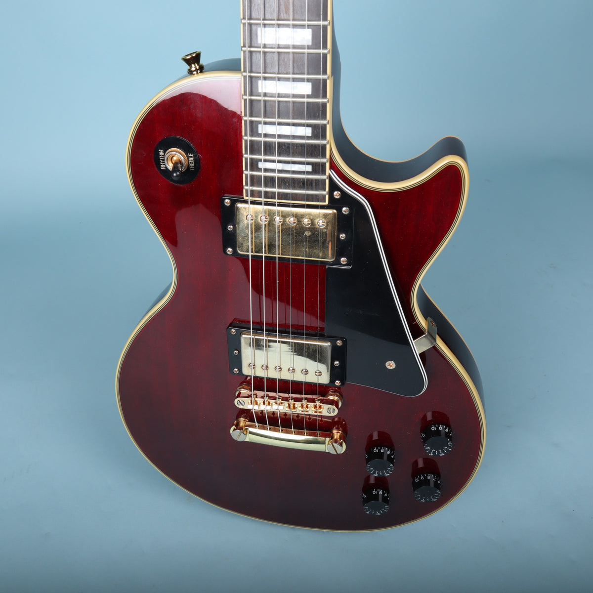 Angled front view of Epiphone Les Paul Custom body showing gold humbuckers and pickguard