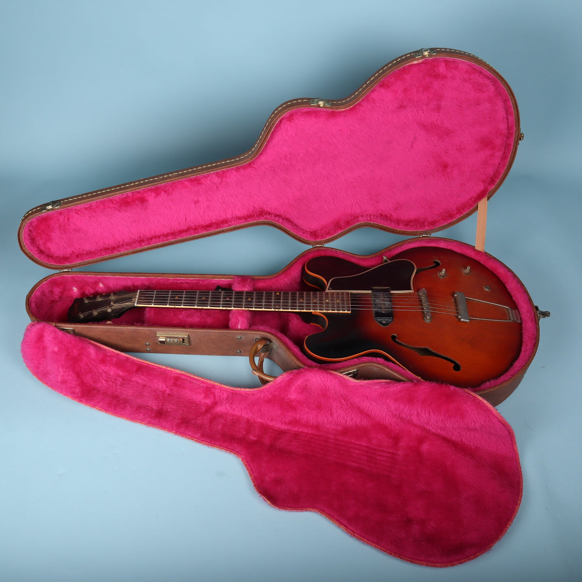Open Gibson case holding a thin hollowbody electric guitar for reference