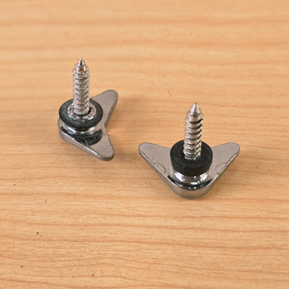 Underside view of two chrome triangular string retainers showing the threaded wood screws and spacers.