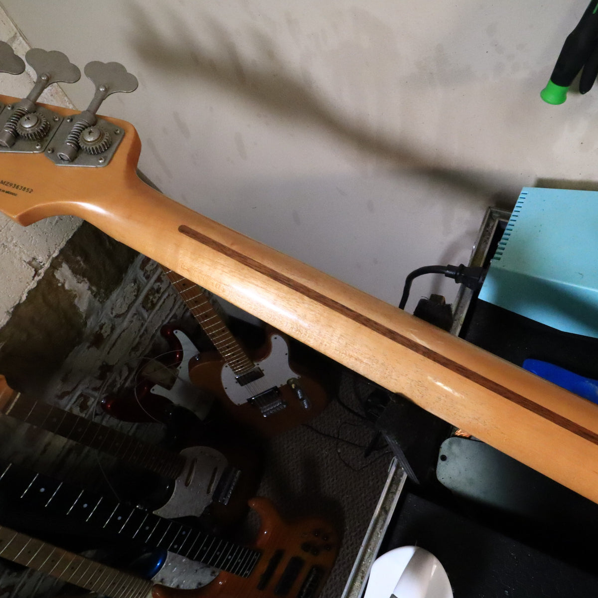 Rear of the maple neck resting on a workbench displaying smooth worn finish.