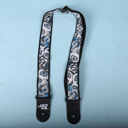 Full overhead view of the Planet Waves Joe Satriani signature guitar strap displayed on a light blue background