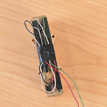 Underside view of bass pickup displaying internal wires taped to bobbin structure.