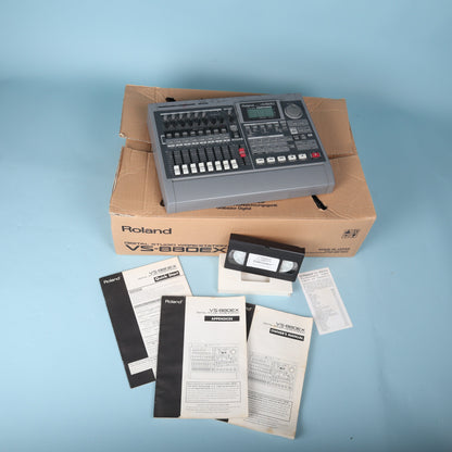 Overhead view showing Roland VS-880EX 8-track recorder with user documentation and video tutorial tape.
