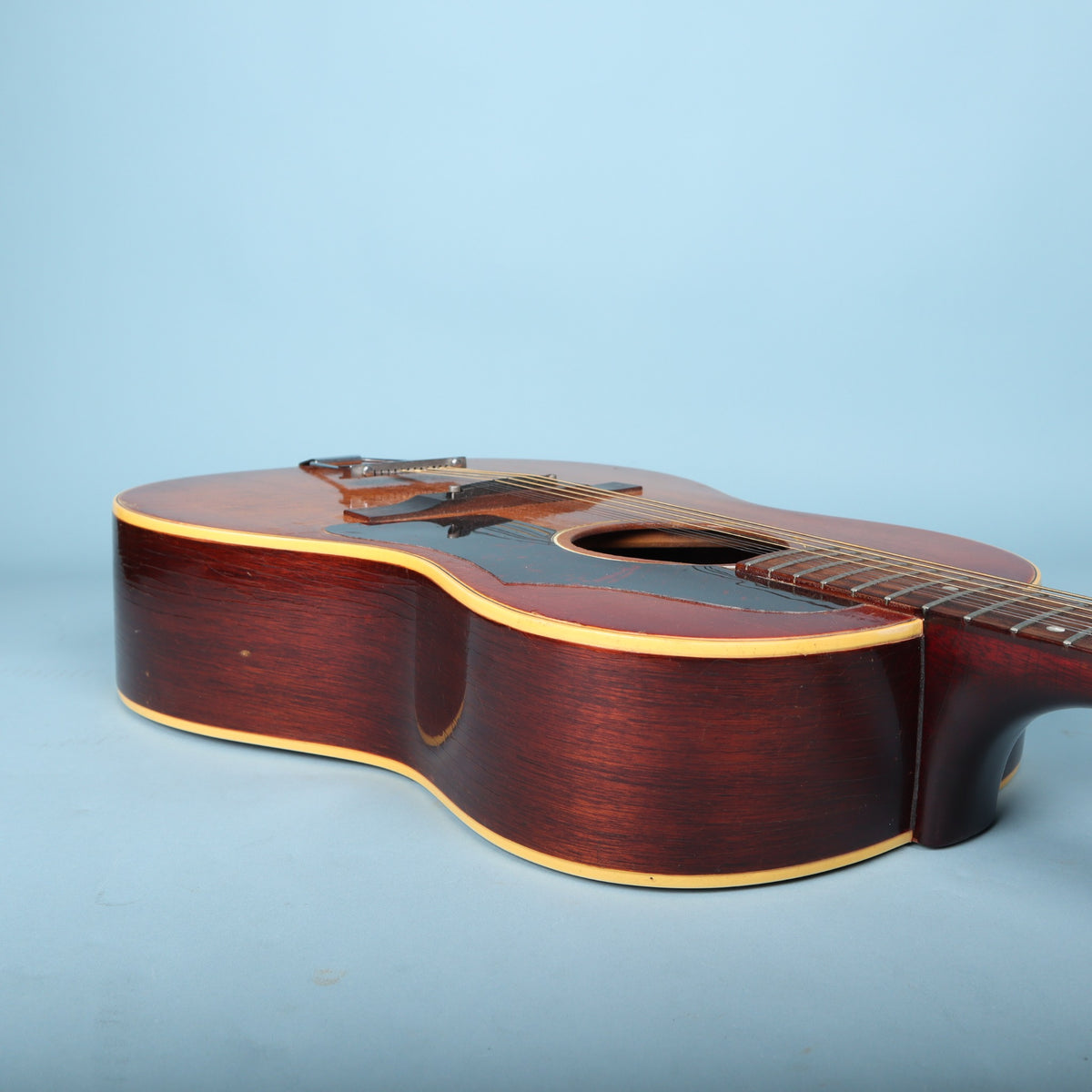 Angled side view of the Gibson B-25-12 body flat on a blue surface.