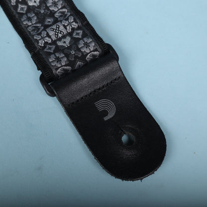 Close-up of the black leather end tab with stamped D'Addario wave logo and button hole.