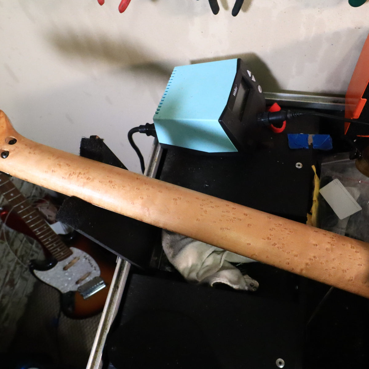 Rear view of birdseye maple neck resting on a workbench.