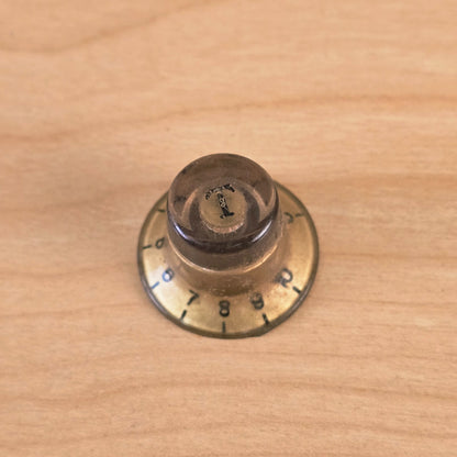 Top-down view of gold top hat guitar control knob with T marker