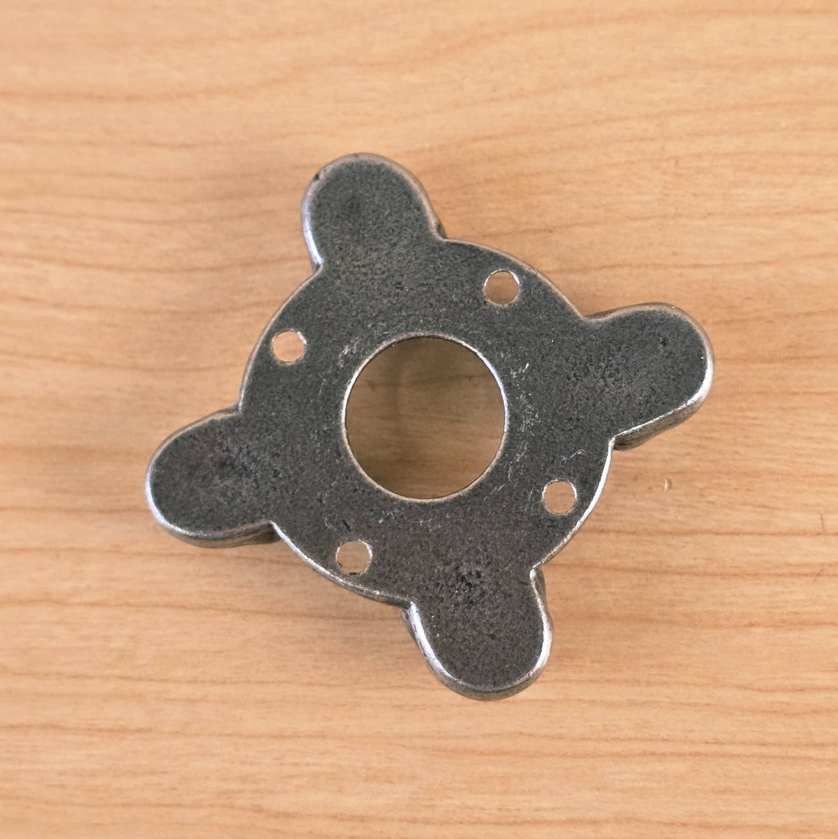 Flat back view of metal part on wood surface