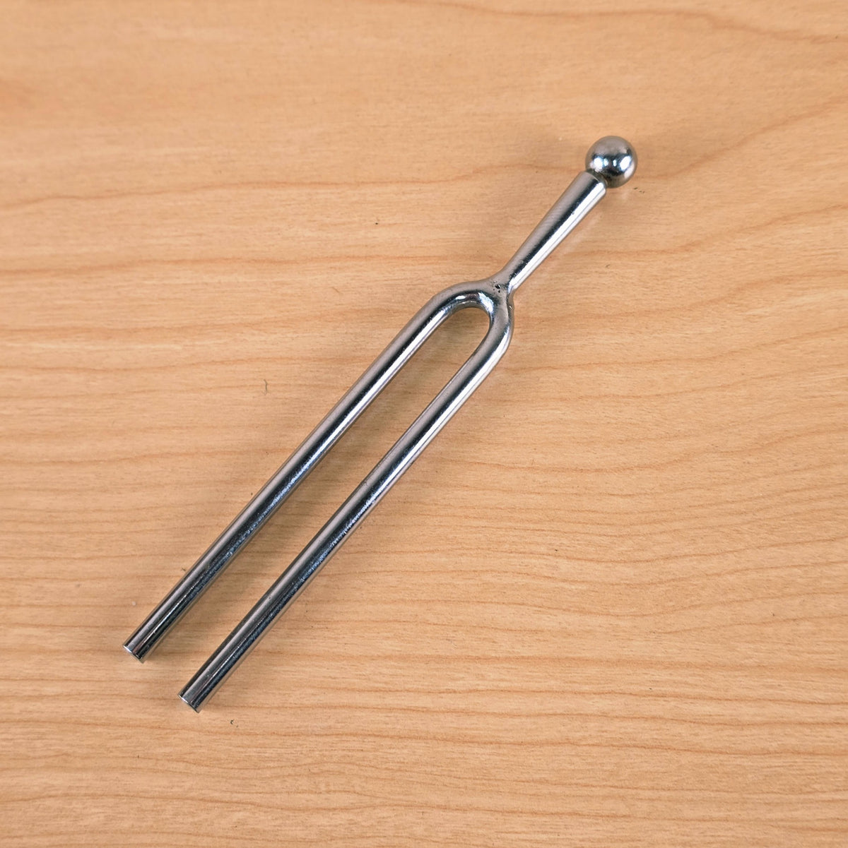 Full view of the A-440 Hz tuning fork resting on a wooden surface