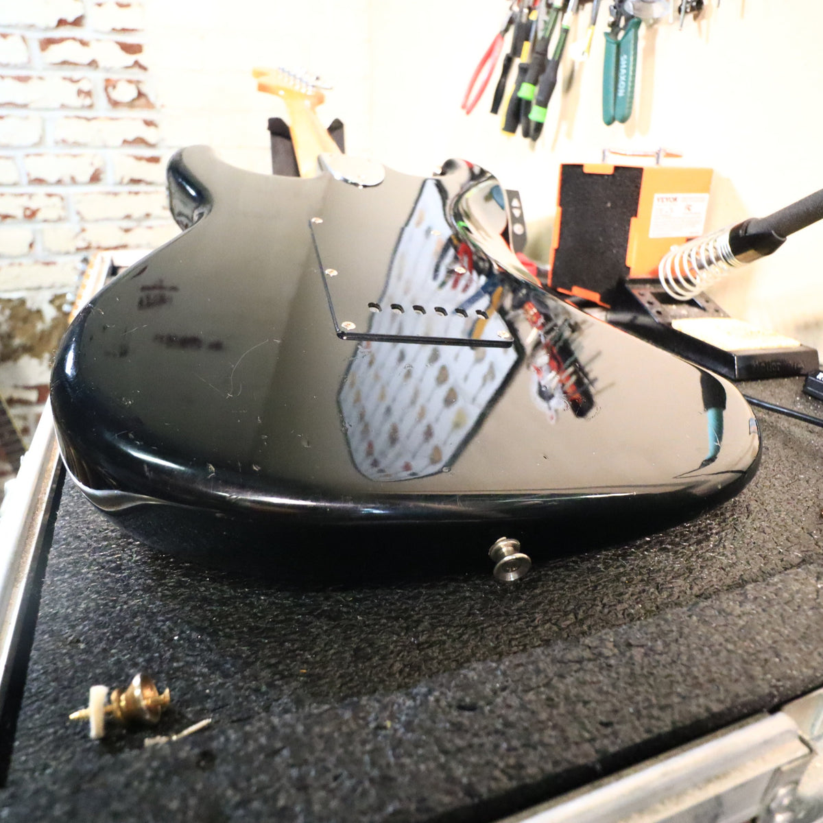 Angled rear view of black guitar body on work bench edge.