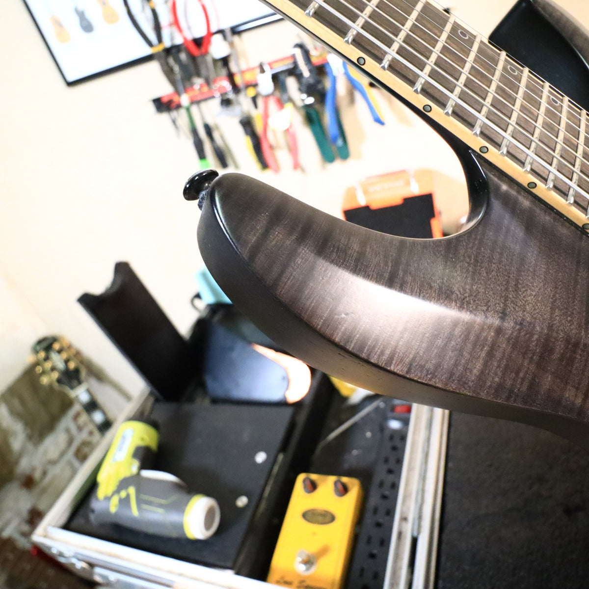 Rear headstock detail on workbench showing Schecter locking tuners and signature graphics
