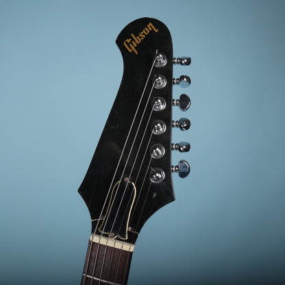 Front view of the black headstock featuring the gold Gibson logo, truss rod cover, and six-in-line tuners.