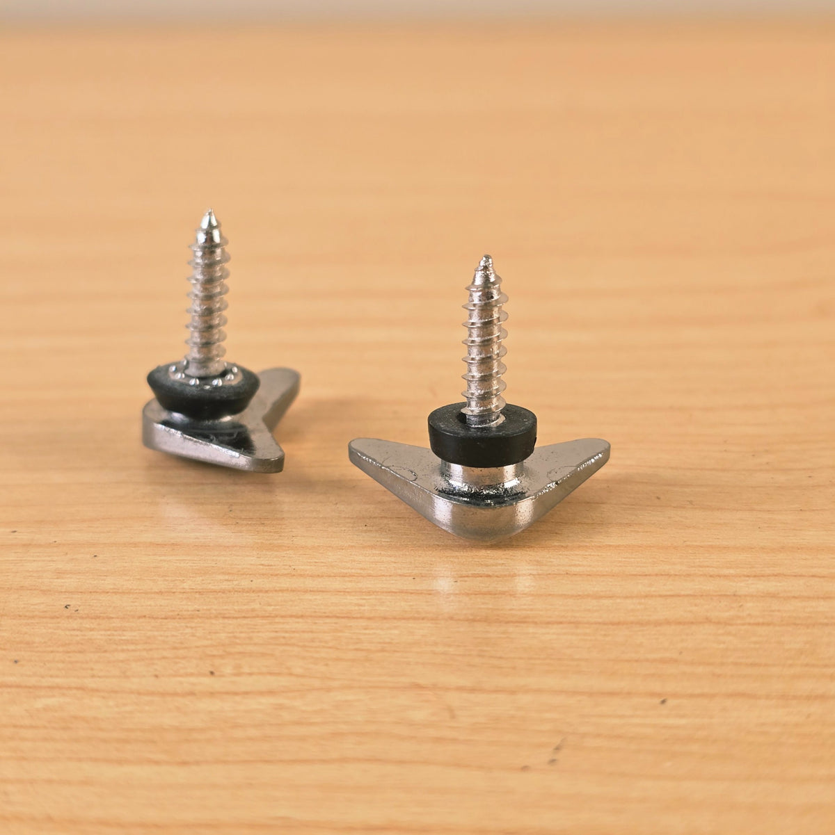 Angled underside view showing the spacer and screw threads on chrome triangular string retainers.