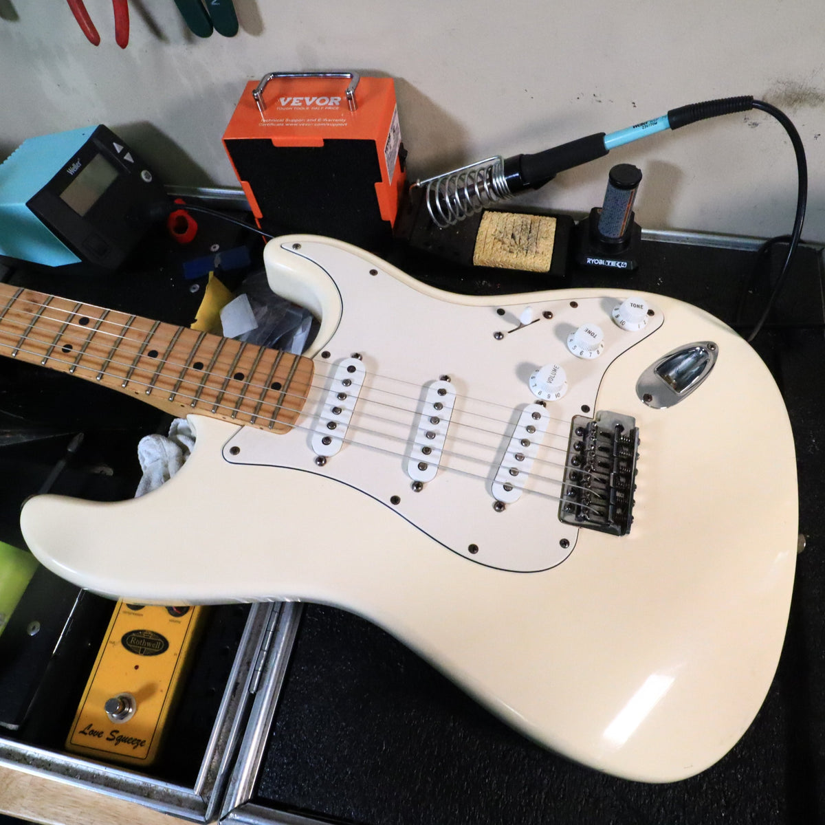 Fender Stratocaster body on workbench showing white finish and pickguard