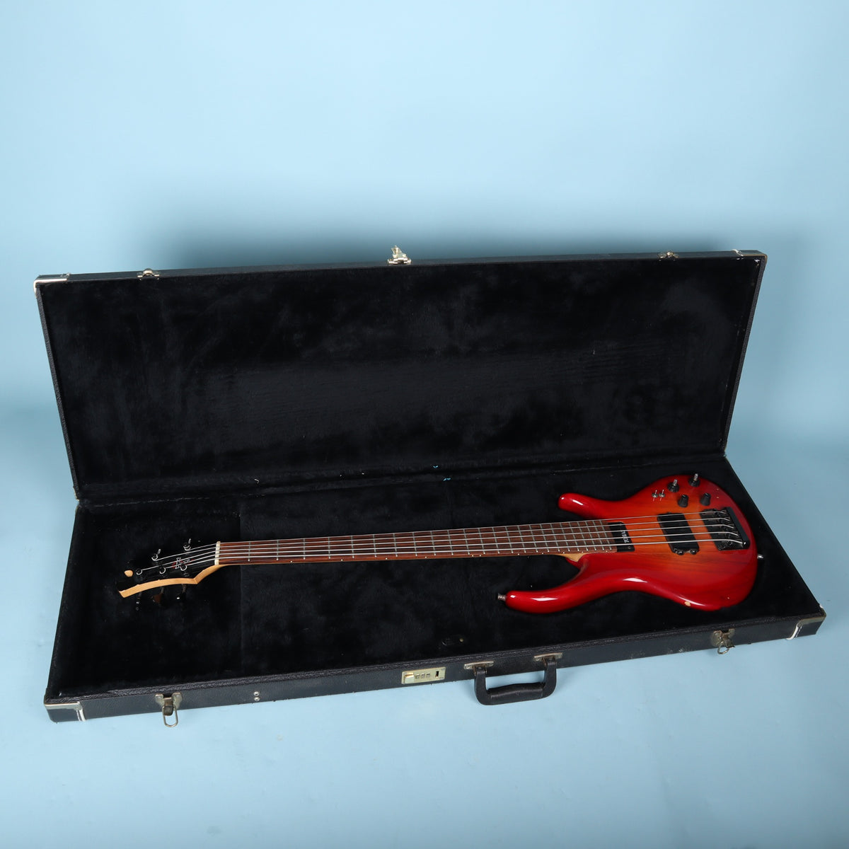 Tobias hardshell bass guitar case open interior showing black plush lining and a reference bass guitar