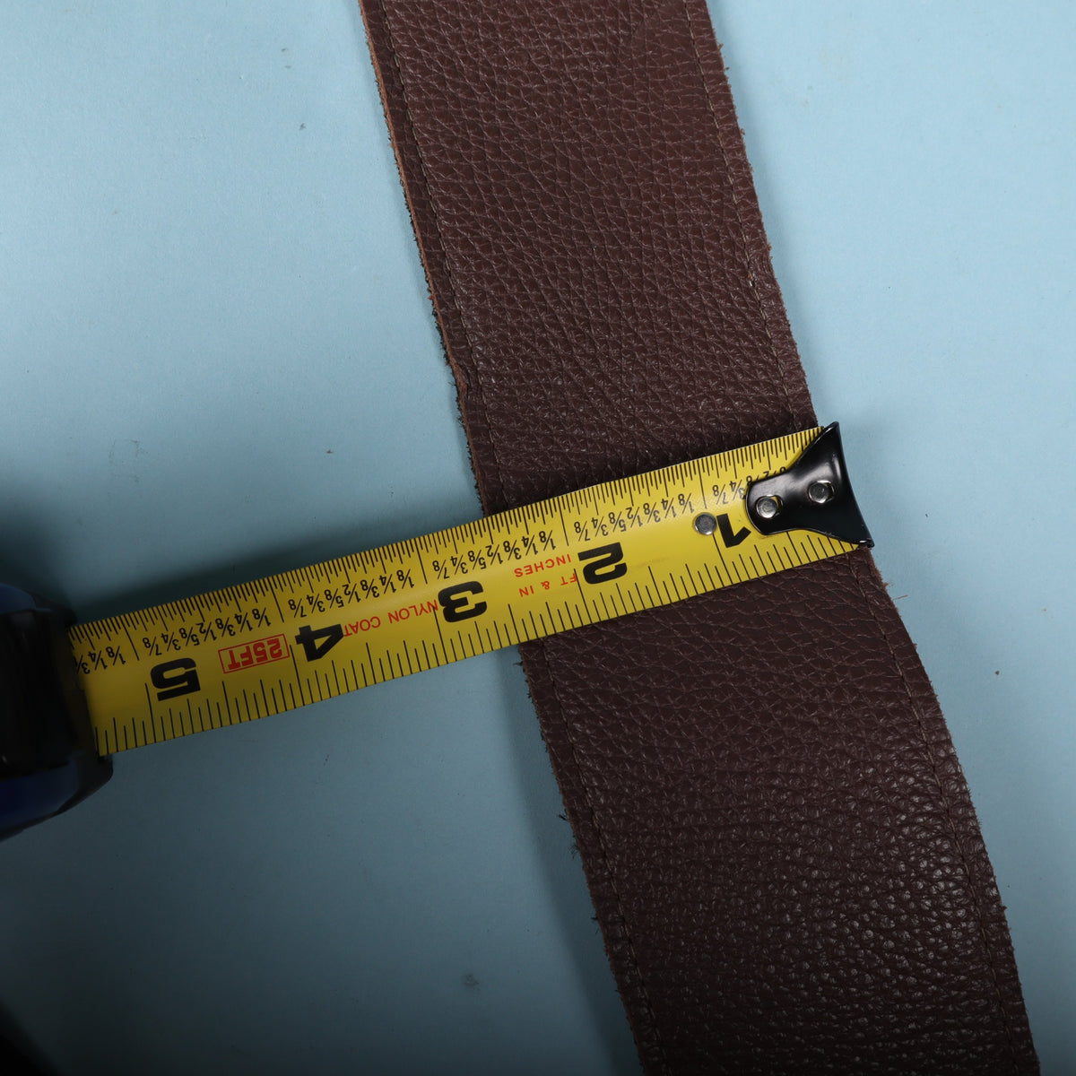 Tape measure across the Levy's leather guitar strap indicating a 2.5-inch width