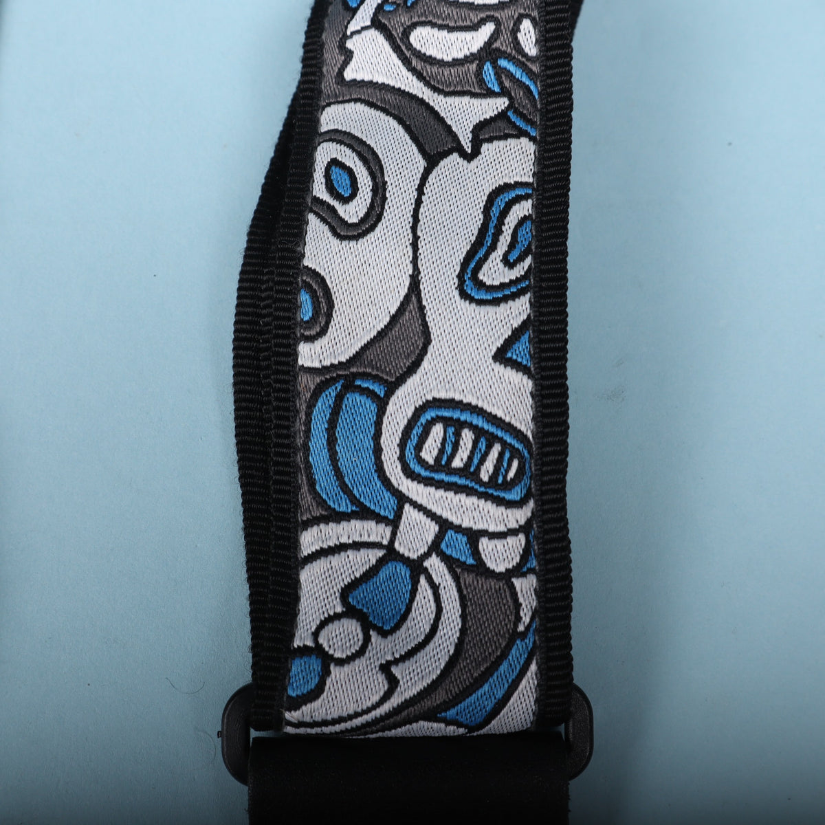 Close-up detail of the woven blue, grey, and white Joe Satriani cartoon artwork on the strap