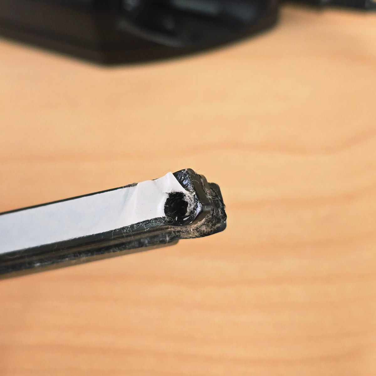 Detail of mounting hole and tape backing on end of Roland GK-2A pickup bar.