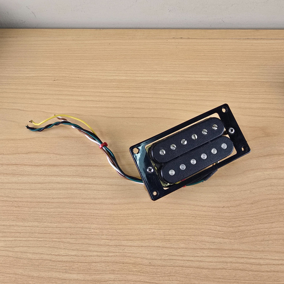 Overhead view of black Schaller humbucker showing coils, poles, and multi-conductor wire lead