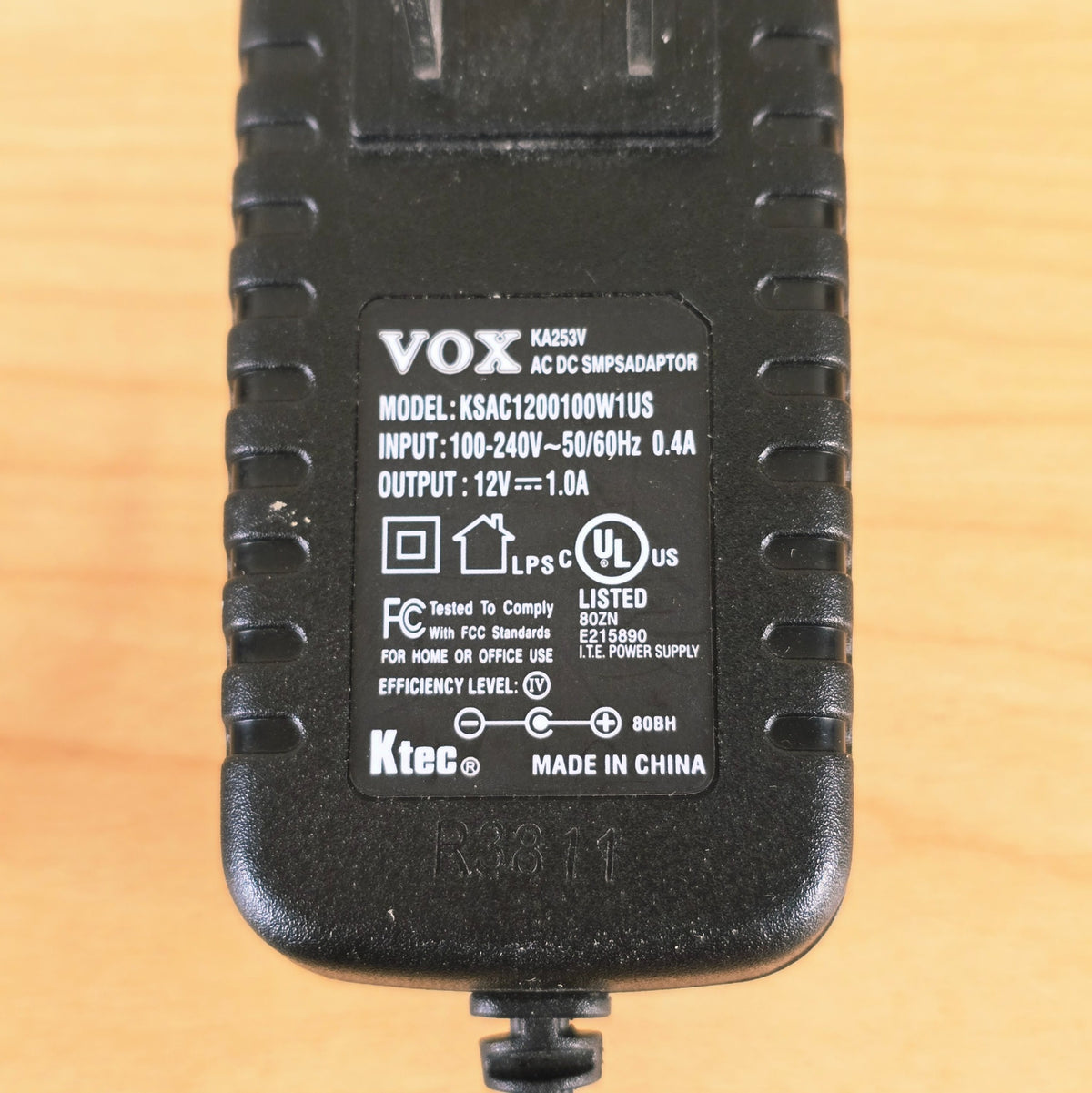 Detailed view of technical label showing 12V 1.0A output and polarity symbol