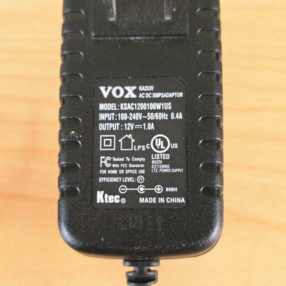 Detailed view of technical label showing 12V 1.0A output and polarity symbol
