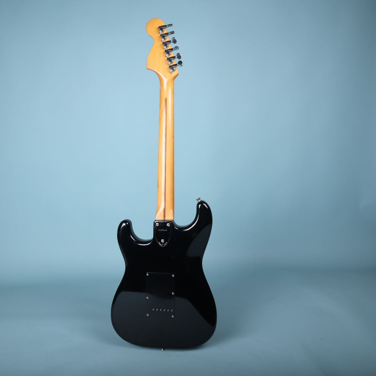 Full rear profile view of Squier Stratocaster electric guitar on blue background.