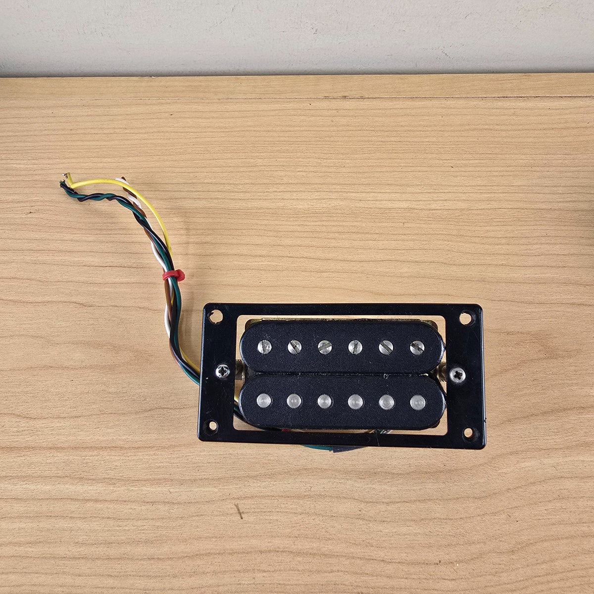 Front face of black open-coil Schaller humbucker mounted in a black pickup ring