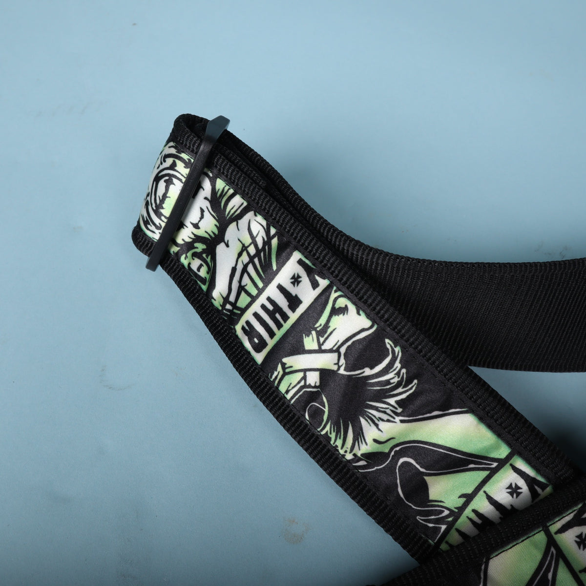 Detail of the plastic adjustment tri-glide buckle and printed webbing on the Dunlop strap.