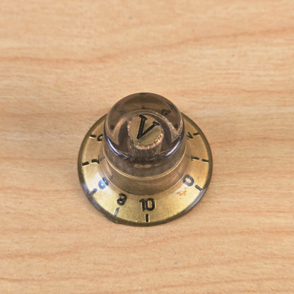 Front-facing top view of gold and transparent control knob with V marker
