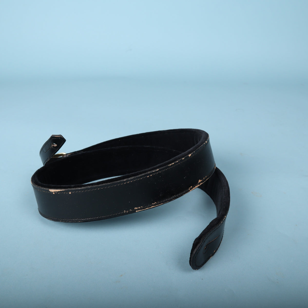 Gretsch black leather guitar strap end featuring strap button mounting slot.