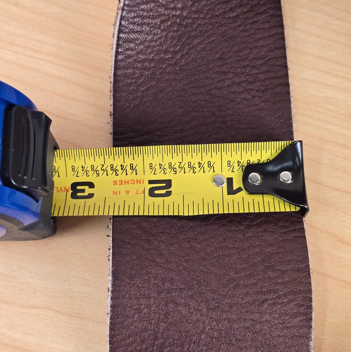 Tape measure showing the Ernie Ball leather strap width measuring 2.5 inches