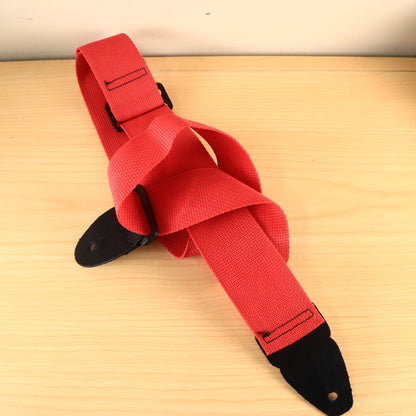 Coiled red guitar strap showing black adjustment hardware and leather end tabs.