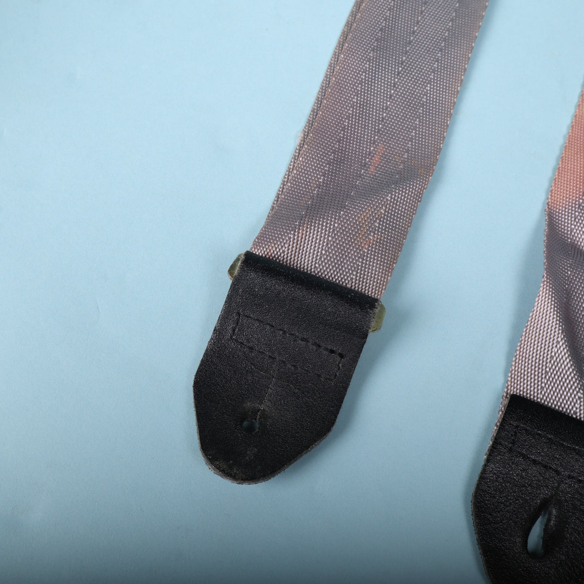 Close-up of the opposite black leather strap end attached to the grey webbing.