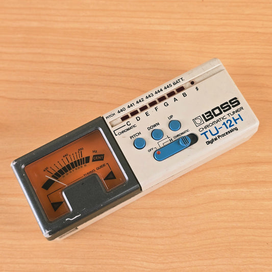 Overhead view of the Boss TU-12H Chromatic Tuner lying on a wooden tabletop.