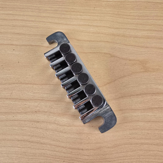 Overhead view of a chrome Gibson TP-6 fine tuning tailpiece on a wood surface