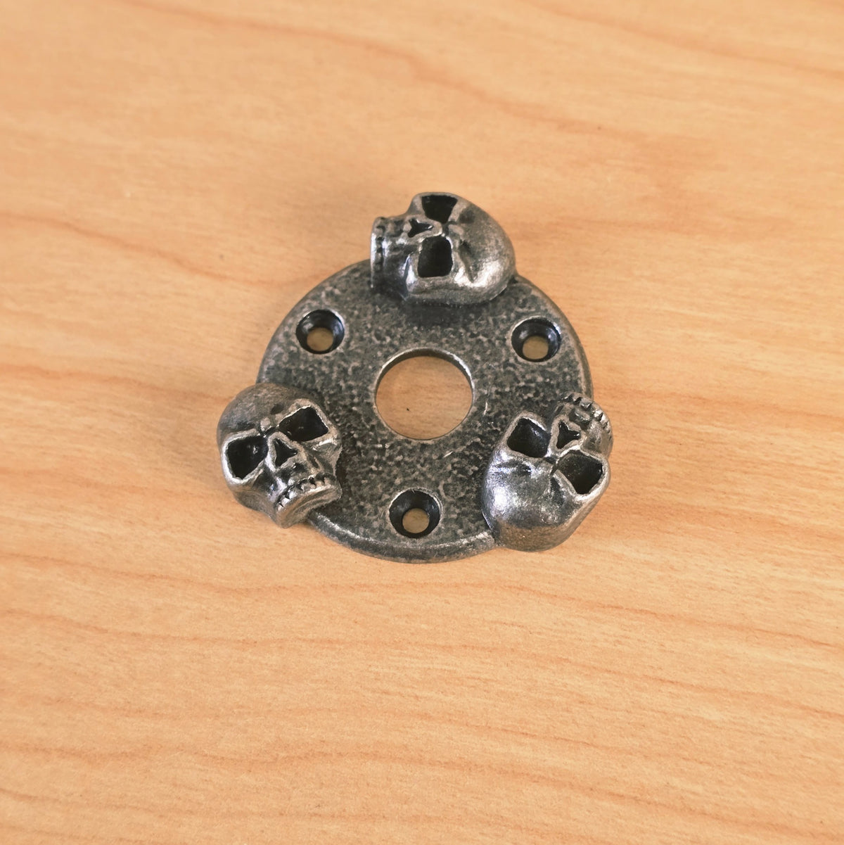 Gunther skull guitar plate angled view showing three sculpted skulls and mounting holes.