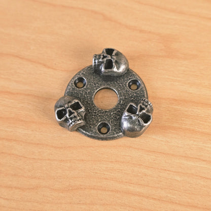 Gunther skull guitar plate angled view showing three sculpted skulls and mounting holes.