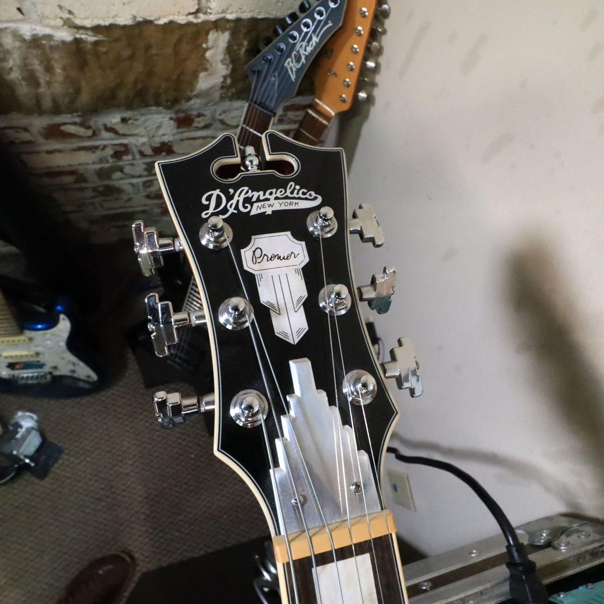 Headstock face of the D'Angelico Premier Mini DC on a workbench.