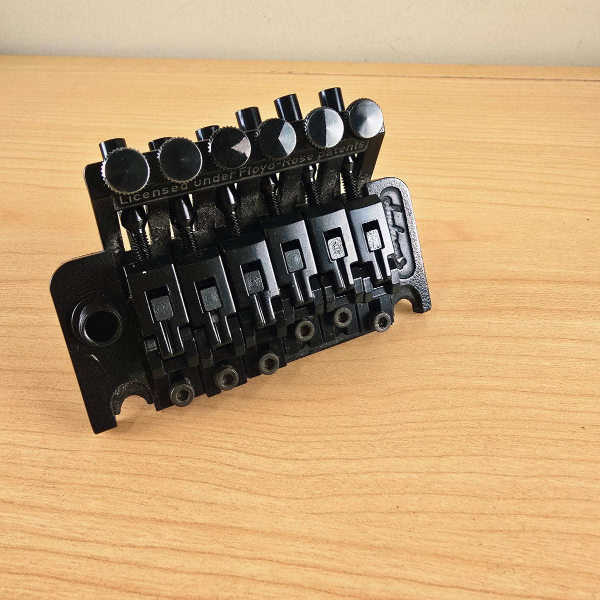 Perspective view of the Jackson tremolo bridge on a light wood surface.